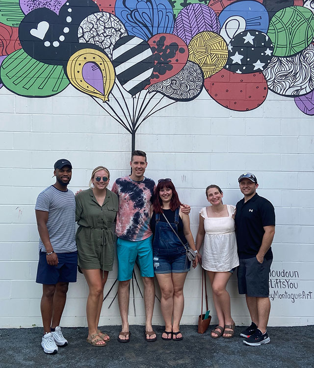 Friends and family in front of a wall with a mural